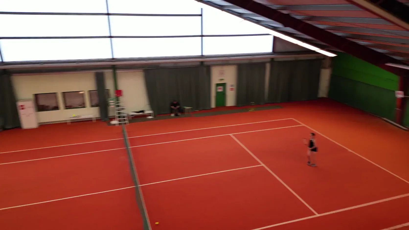 Blick in die Hembacher Sportarena mit einem Spieler auf dem Tennisplatz
